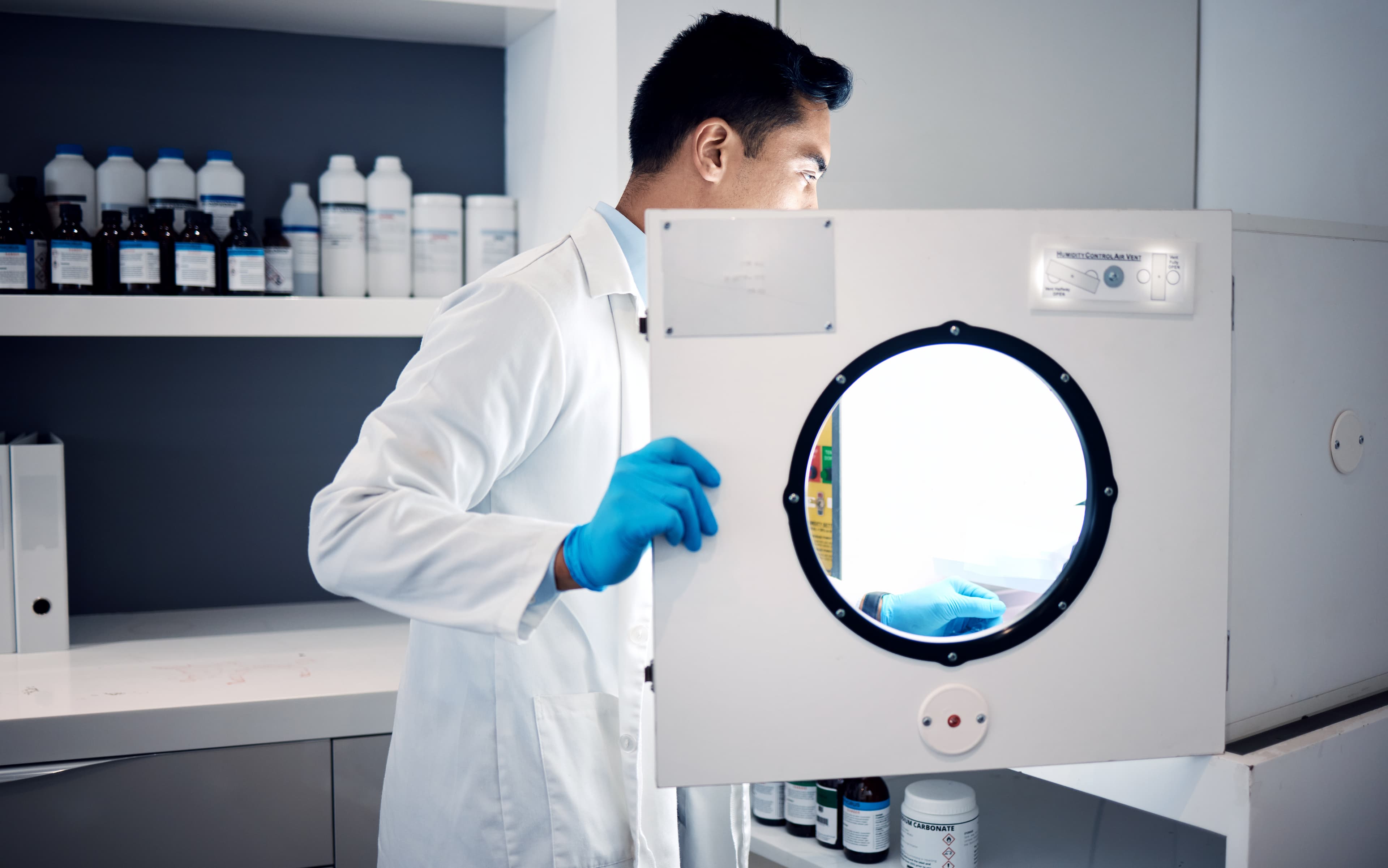 Pracownik otwiera drzwi komory urządzenia laboratoryjnego