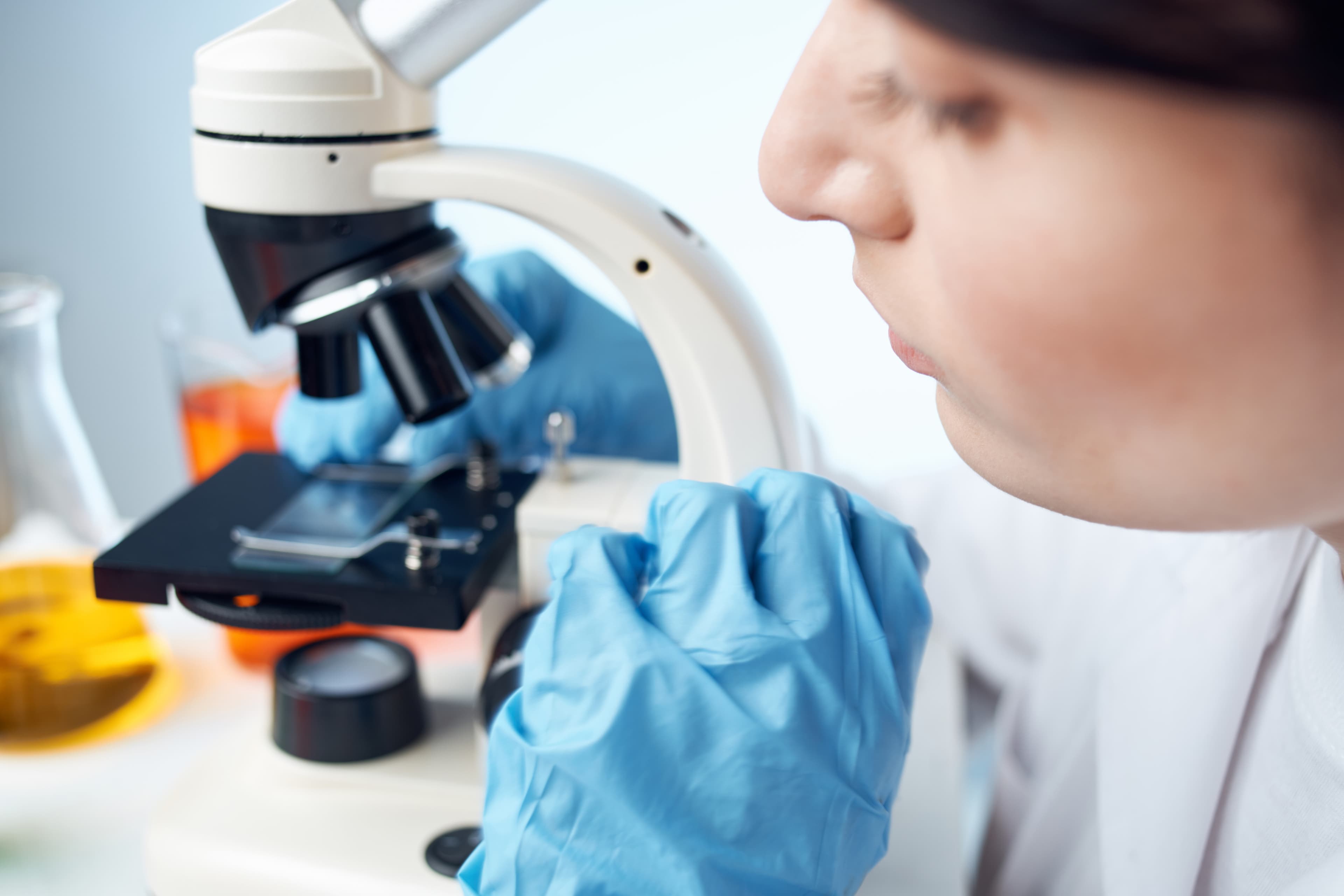 Osoba prowadzi obserwację przy mikroskopie laboratoryjnym