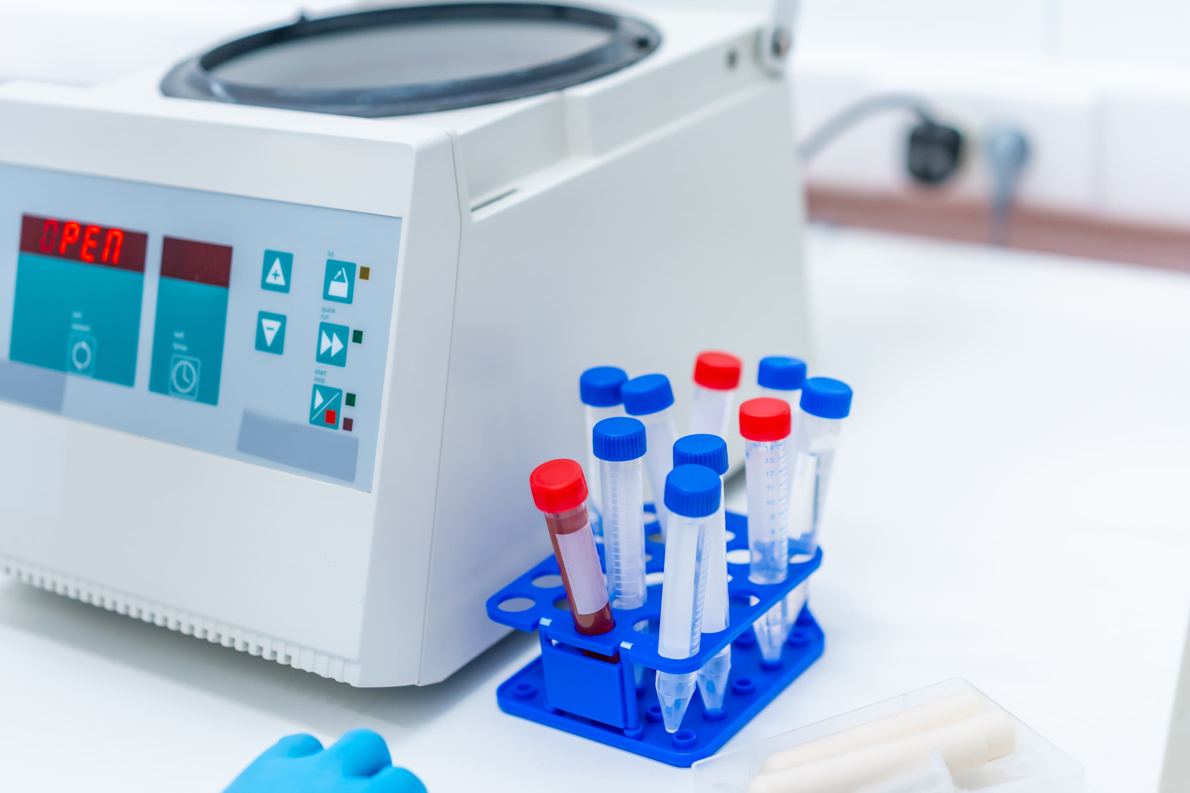 Wirówka laboratoryjna obok statywu z probówkami