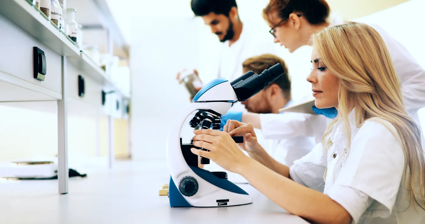 Zespół studentów pracujący przy mikroskopie w laboratorium